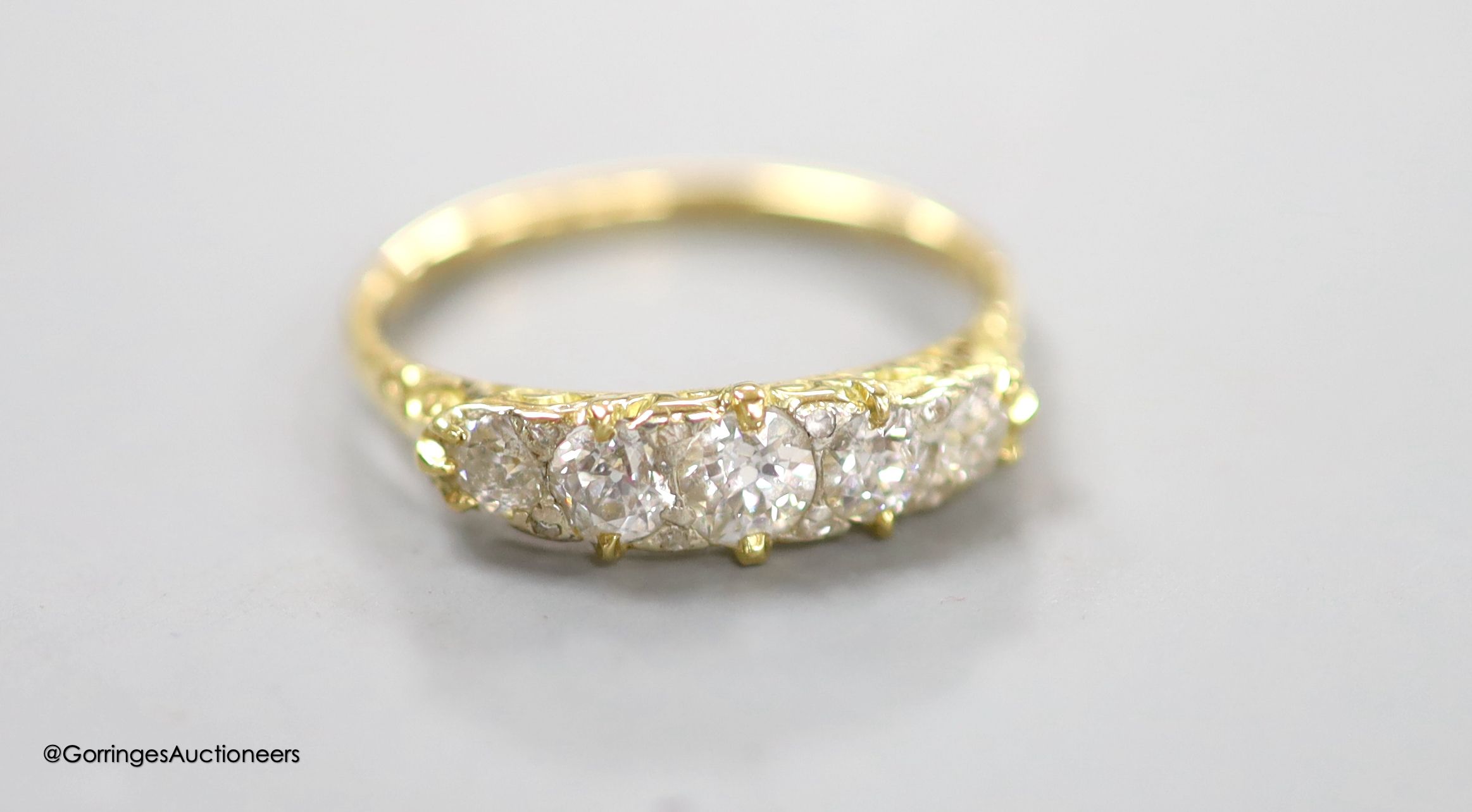 An early 20th century 18ct and graduated five stone diamond set half hoop ring, with diamond chip spacers and carved shoulders, size P, gross weight 2.8 grams